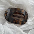 Detail of tortoiseshell claw clip with hollow stripe design on white textured paper - 10cm Oval Coffee Tortoiseshell