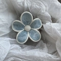 Vue détaillée de la pince à cheveux florale avec motifs marbrés et pétales bleu pastel élégants - Bleu gris