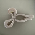 Detailed macro view of an elegant nude pink bow hair claw clip with a glossy finish - Light Gray