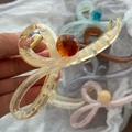Dettaglio di grandi mollette per capelli in acrilico con design a vortice e perla elegante - Motivo a Flusso Champagne