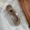 Dettaglio di una grande molletta per capelli in acetato venato di legno su carta bianca - Stile Uovo Grana del Legno Caffè