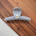 Detail of grey hair claw clip featuring golden bow and white marble textured square - Gray White Bow