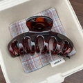 Detail einer bernsteinbraunen Haarklammer mit glänzendem Finish auf Plaid-Stoff - Glänzend Rotes Schildpatt