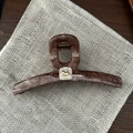 Detalle de pinza para el cabello en acetato jaspeado con emblema de cachorro dorado y blanco - Patrón de mármol café oscuro (Logo de cachorro)