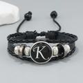 Macro detail of multi-layer black leather bracelet featuring letter K and metal beads - Letter K