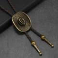 Primo piano della cravatta bolo in bronzo con emblema del cappello da cowboy e corda in cuoio - Pelle Marrone + Bronzo