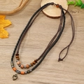 Vintage layered woven necklace with heart pendant and wooden beads on wood background - Heart