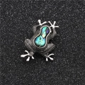 Elegante zilveren kikkerbroche met kleurrijke abalone inleg op een zwarte achtergrond - Kikker