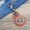 Vintage brown leather keychain with metal star pendant on a wooden surface - Tan
