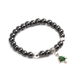 Detail eines magnetischen Hämatit-Perlenarmbands mit grünem Weihnachtsbaum-Anhänger - Silberner Weihnachtsbaum