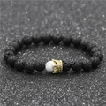 Detail of black lava stone bracelet with white turquoise bead and gold zircon crown charm - Volcanic Stone Small Crown