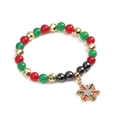 Vue détaillée du bracelet de Noël avec perles rouges, vertes et breloque flocon de neige dorée - Flocon de Neige Doré