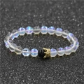 Bracelet en perles de pierre de lune avec breloque couronne dorée sur fond noir pailleté - Pierre De Lune Avec Une Agate Noire