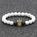 Macro shot of white turquoise beads with a golden crown charm and black lava stones - White Turquoise Big Crown