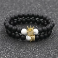 Dettaglio dei ciondoli a corona dorati con zirconi su bracciali di perline bianche e nere - Corona Grande Nero Opaco E Corona Piccola Nero Opaco