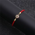 Macro view of red rope bracelet with colorful zircon pavé evil eye charm and gold plating - Round Multicolor Zirconia