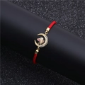 Detailed close-up of red woven bracelet with gold moon and bee charm inset with colorful zircons - Moon Bee