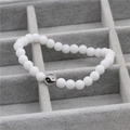 Detail van witte kralenarmband met yin yang bedeltje in een grijze juwelendoos - Witte Steen