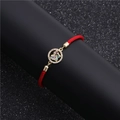 Detailed macro of red cord bracelet with gold butterfly charm and zircon inlay - Circular Butterfly