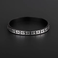 Detail of matte black titanium steel ring with silver Greek key pattern on dark background - Black