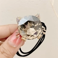 Cute cat hair tie with grey crystal and gold details shown in a hand close-up - Gray