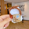 Brown elastic hair tie featuring a golden bee charm and iridescent gemstone square - Square Champagne