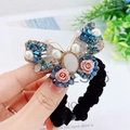 Chouchou papillon avec cristaux bleus et rose en résine rose tenu dans la main - Corde à Cheveux Papillon Rose
