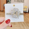 Eleganter Kleeblatt-Haarclip mit Gold-Finish und funkelnden Kristallen auf Karte - Vierblättriges Kleeblatt-Stil