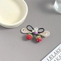 Detailaufnahme der Erdbeeren-Haarklammer mit roten Kristallen und Schleife - Erdbeere Schwarz