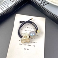 Close-up of cute bear charm with rhinestones and large pearl on a black elastic hair tie - White