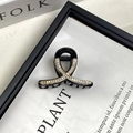 Dettaglio di un fermaglio a molletta nero a fiocco con strass e accenti dorati lucidi - 4.5CM Nero Pietra Bianca