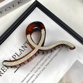 Macro view of a large tortoise resin hair claw with rhinestones and gold-tone edging - Geometric Line Coffee with White Rhinestones