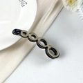 Dettaglio di un fermaglio a banana nero con quattro ovali dorati e strass lucidi - Fermaglio a Banana a Cerchi Collegati (DH01249) / Nero Con Strass Bianchi