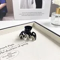Elegante molletta per capelli nera con strass esposta su un vassoio color crema - Onda Piccola / Nero con Zirconia Bianca
