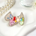 Vue macro détaillée d'une barrette en forme de nœud avec strass colorés et motif Hello - Chiot Champagne