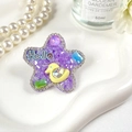 Vue détaillée d'une barrette étoile violette avec strass colorés et un petit canard jaune - Étoile Violette