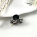 Primer plano de una mini pinza para el cabello con pedrería sobre fondo de perlas - Negro Fresco Con Flor Gris