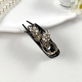 Detail van vintage haarklem met strass steentjes en gouden bladeren op zwarte glanzende klem - Tarwearen Stijl