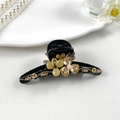 Detailaufnahme der bernsteinfarbenen Blumen-Haarklammer mit Goldketten auf weißem Teller - Haargreifer / Gelb