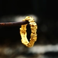 Macro shot of gold-plated skull ring hanging on rusty wire with dark blurred background - US Size 7 / Gold
