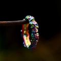 Macro shot of gothic iridescent skull ring on rusty metal bar with rainbow plating detail - Colorful