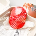 Detail of red marble texture oval hair comb with gold eyelet in premium packaging - Orange Red Marble