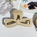 Macro detail of cream bow-shaped hair claw clip with smooth finish on a minimalist desk - Milk Coffee