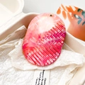 Gros plan d'un peigne en résine marbrée rose avec boucle dorée élégante et dents intégrées - Marbre Orange Coloré