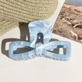 Detailopname van blauwe marmeren haarclip met strik op een beige zachte ondergrond - Grijsblauw