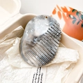 Detailed macro view of an oval marble textured hair comb in a minimalist gift box - Grey Black Marble