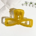 Detail shot of a translucent ginger yellow bow-shaped hair claw clip on a textured surface - 9.5cm Transparent Ginger Yellow