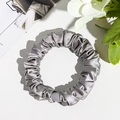 Close-up of a silver-grey satin silk scrunchie with elegant pleated texture on leather - Silk Pleated Small Scrunchie - Silver Gray