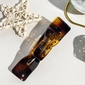Macro di un fermaglio per capelli tartarugato con fiocco su sfondo di pelle bianca chic - Tartarugato Lucido