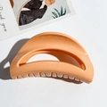 Detail of orange crescent-shaped hair claw clip with smooth UV finish on art card - Orange Moon Style